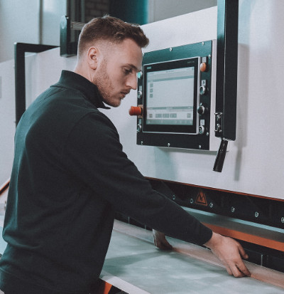 A close-up photo of a KUPER engineer servicing a veneering machine