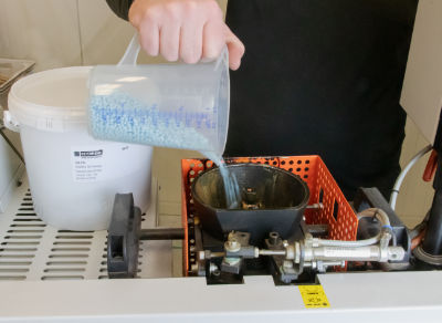 An image of glue pellets being loaded into the edgebander gluepot